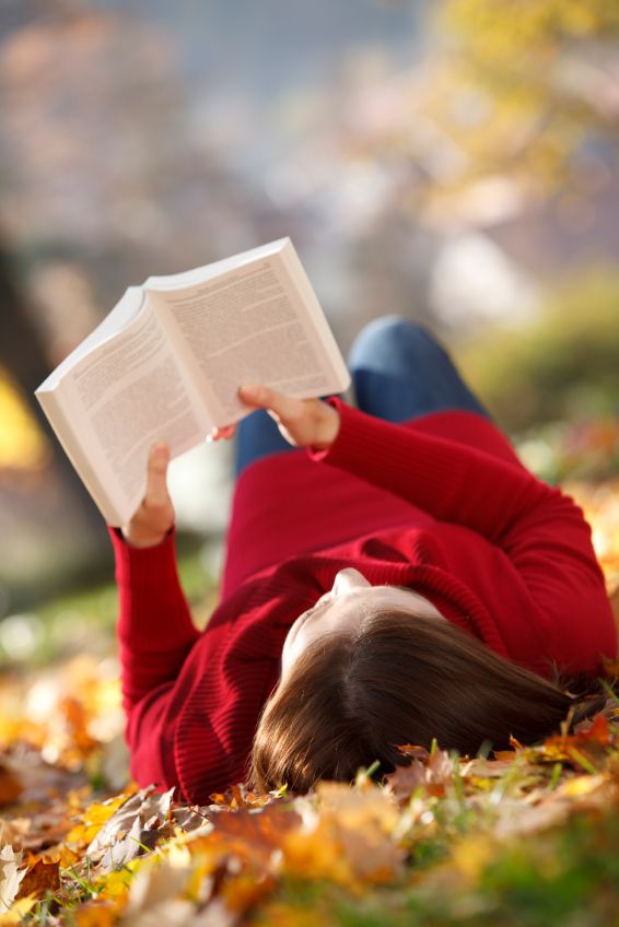 Young woman reading a book and enjoying autumn